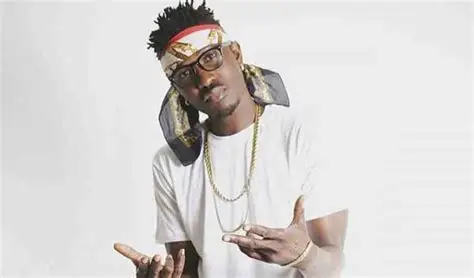 Tinny performing on stage, representing Ga culture through music.