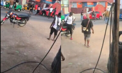 Two men exchange punches in a heated street fight as bystanders attempt to separate them.