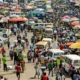 Trader at Ghanaian market expressing concern over unchanged prices despite fuel and cedi improvements