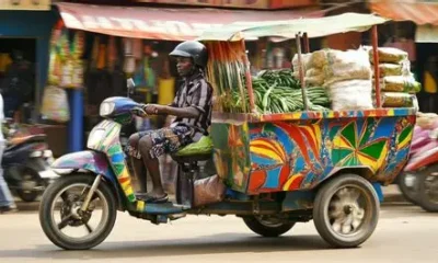 Commercial tricycle (aboboyaa) transporting goods on a Ghanaian road