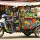 Commercial tricycle (aboboyaa) transporting goods on a Ghanaian road